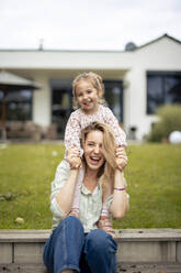 Happy mother holding hands and enjoying with daughter in front of house - JOSEF23170