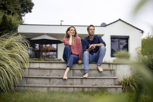 Lächelnde Frau und Mann sitzen vor einem Haus - JOSEF23256