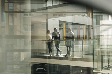 Business colleagues having discussion on walkway at office - UUF31121