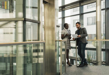 Business colleagues having discussion in corridor at office - UUF31124