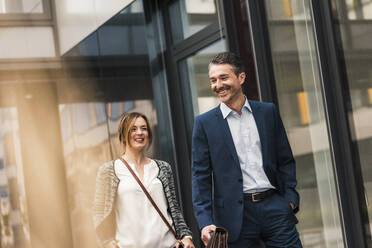 Happy coworkers walking near office building - UUF31132