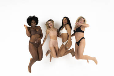 Models of different ages celebrating their natural and aging bodies. Four  body positive and confident women wearing black underwear and standing  together in a studio. stock photo