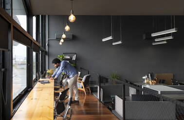 Young businessman working on laptop at desk in office - VRAF00288