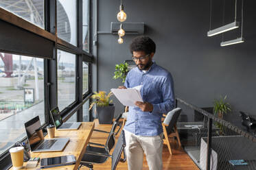 Young businessman examining documents in office - VRAF00290