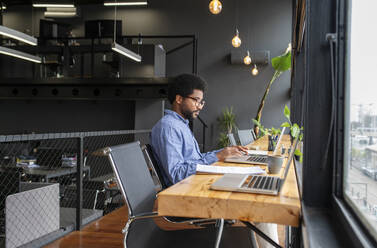 Businessman working on laptop in office - VRAF00295