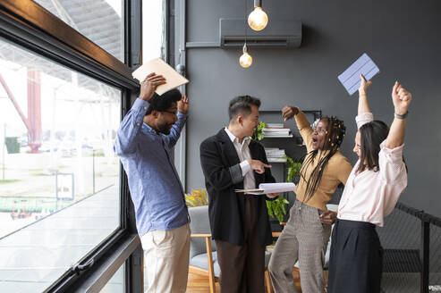 Happy businessman with colleagues cheering in office - VRAF00335