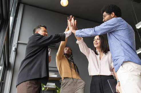 Happy colleagues giving high-five to each other in office - VRAF00336