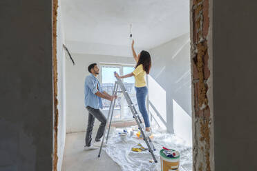 Young couple installing light bulb at new home - AAZF01444