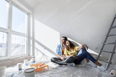 Happy couple sitting on floor at new home - AAZF01463