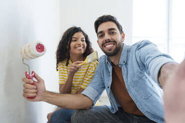 Verspieltes Paar mit Malutensilien macht Selfie im neuen Haus - AAZF01469