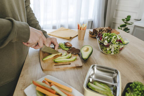 Mann schneidet Avocado mit Messer in Küche zu Hause - YTF01680