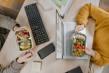 Freelancers working and having lunch at table - YTF01689