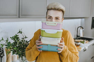 Young woman holding lunch boxes in kitchen at home - YTF01691