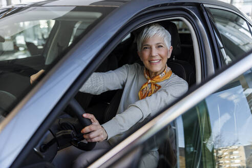 Happy senior woman sitting in car - IKF01613