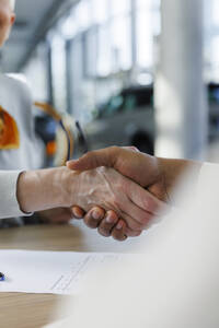 Frau schüttelt Hände mit Autoverkäufer am Schreibtisch - IKF01648