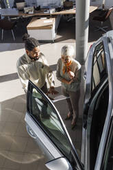 Autoverkäufer, der mit einem Kunden über ein Dokument spricht - IKF01663