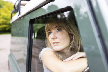 Young beautiful woman looking through car window - WPEF08256