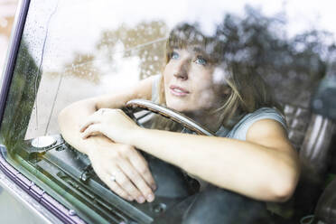 Thoughtful beautiful woman looking through car window - WPEF08260