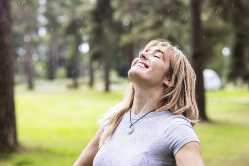 Happy young woman enjoying rain in forest - WPEF08271