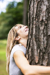 Happy beautiful woman hugging tree - WPEF08287
