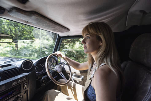 Junge schöne Frau fährt Auto an einem sonnigen Tag - WPEF08328