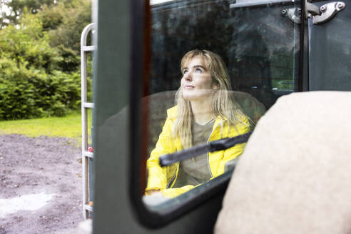 Smiling young blond woman sitting in car - WPEF08334
