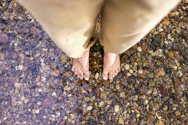 Woman standing in river water on stones - WPEF08357