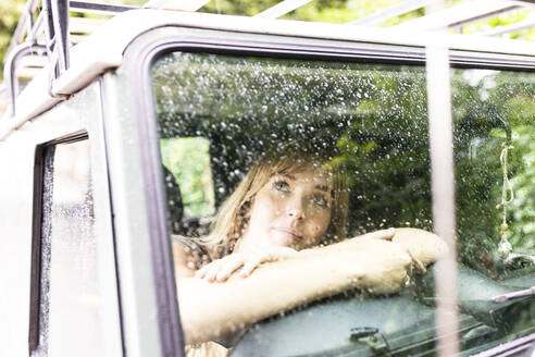 Woman sitting and looking through car window - WPEF08376