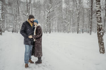 Älteres Paar steht im Schnee im Park - ANAF02702