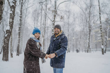 Glückliches Paar hält sich im Snowpark an den Händen - ANAF02708