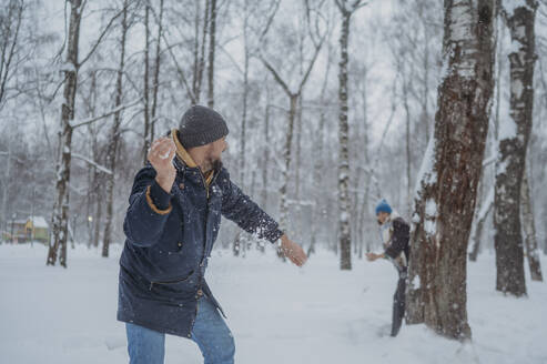 Älteres Paar spielt mit Schneeball im Park - ANAF02713