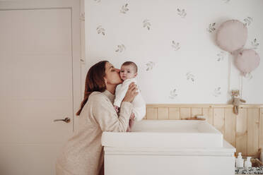 Liebevolle Mutter küsst ihr kleines Mädchen zu Hause - EBBF08387