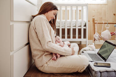Freelancer sitzt mit Baby-Mädchen in der Nähe von Laptop im Büro zu Hause - EBBF08391