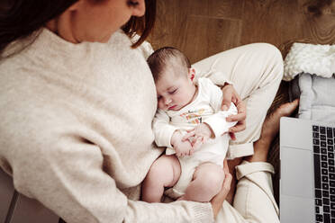 Mother sitting on floor with daughter at home - EBBF08392