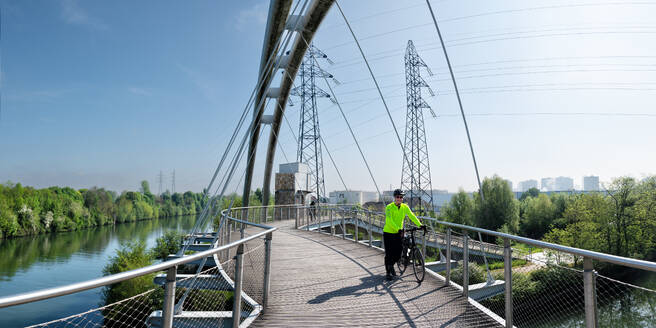 Älterer Mann zu Fuß mit Fahrrad auf der Brücke Dessau Modern in Deutschland - ALRF02108
