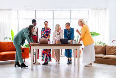 Group of beautiful confident businesswomen meeting in the office - Multiethinc female creative team brainstorming at work - Diverse colleagues working together in workshop in a co-working space - DMDF09701