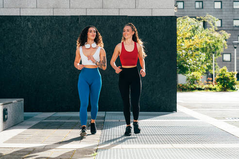 Ein schwules Paar trainiert zusammen im Freien. Ein echtes Läuferpaar treibt Sport in einem urbanen Gebiet der Stadt. Konzepte von Sport und Lifestyle - DMDF09833