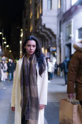 Junge Frau mit Schal und Mantel in der Stadt bei Nacht - PBTF00439