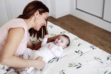 Glückliche Mutter spielt mit Baby Mädchen auf dem Bett zu Hause - EBBF08409
