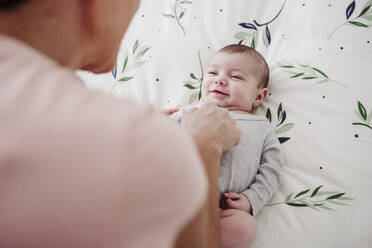 Süßes Baby lächelnd in der Nähe von Mutter zu Hause - EBBF08435