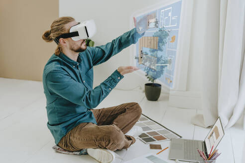 Innenarchitektin bei der Vorbereitung eines Projekts durch eine VR-Brille, die auf dem Boden im Büro sitzt - YTF01733