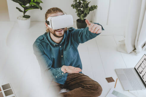 Lächelnder Innenarchitekt mit VR-Brille und Gesten im Büro - YTF01736