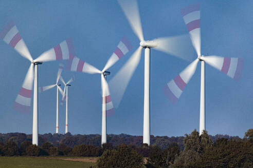 Spinning wind farm turbines in rural landscape - JATF01378