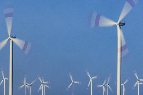 Wind farm turbines spinning against blue sky - JATF01384