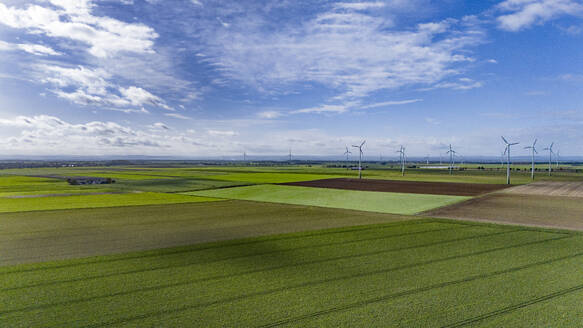Aerial view of countryside fields with wind farm in background - JATF01390