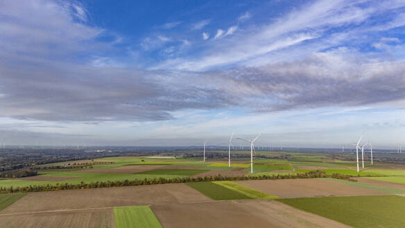 Aerial view of clouds over countryside fields with wind farm in background - JATF01393