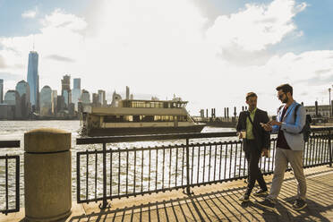 Young business colleagues walking on promenade in city - UUF31138