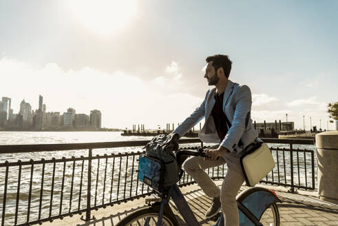 Businessman cycling on promenade in city - UUF31145
