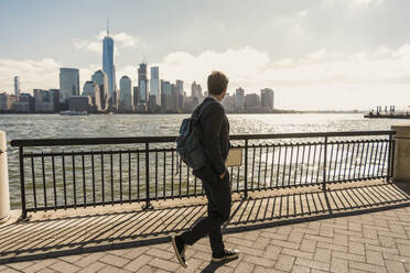 Geschäftsmann mit Blick auf die Skyline und Spaziergang auf der Promenade in der Stadt - UUF31146