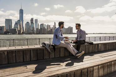 Business colleagues discussing on bench at promenade in city - UUF31150